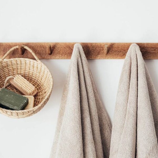 Bathroom decor accessories featuring cotten towels and a wooden woven storage basket on hangars