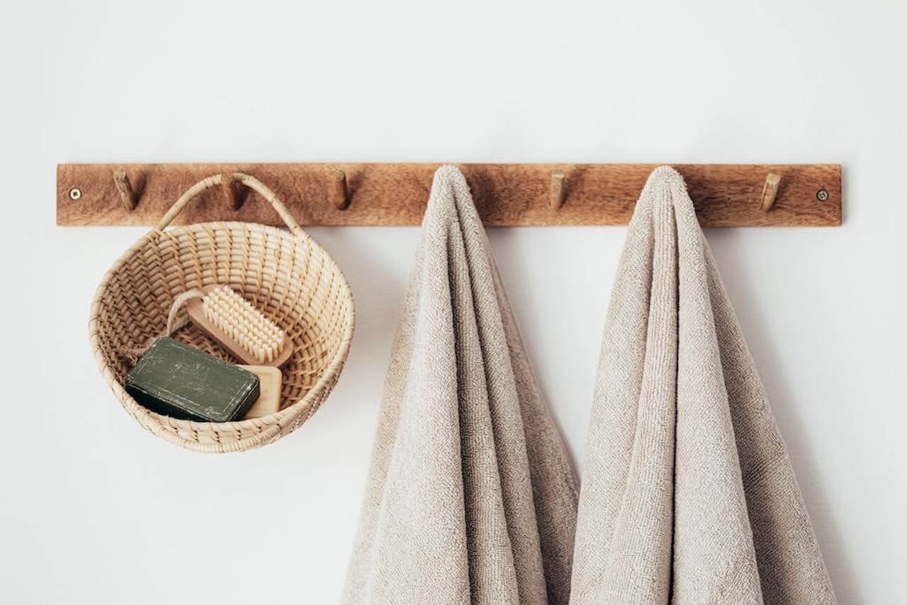 Bathroom decor accessories featuring cotten towels and a wooden woven storage basket on hangars