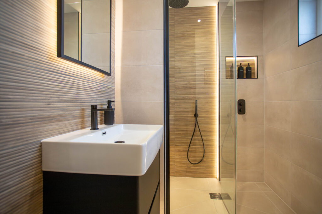 Modern bathroom with a vessel sink, black fixtures, and a walk-in shower with subtle strip lighting.